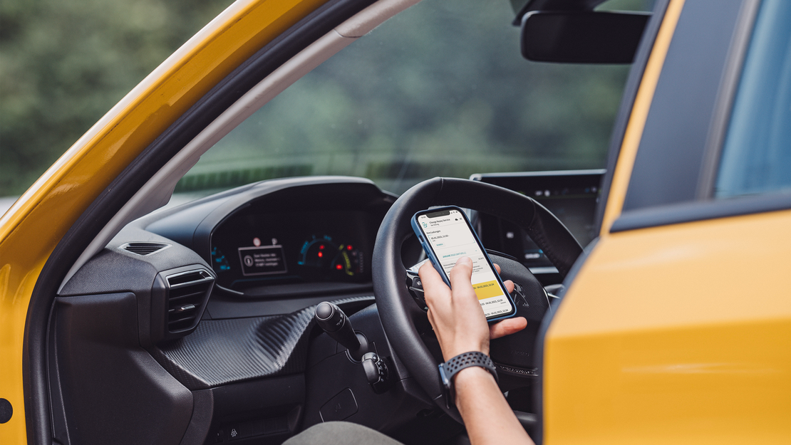 Dienstwagenfahrer mit auf dem Smartphone geöffneten Charge Repay Service