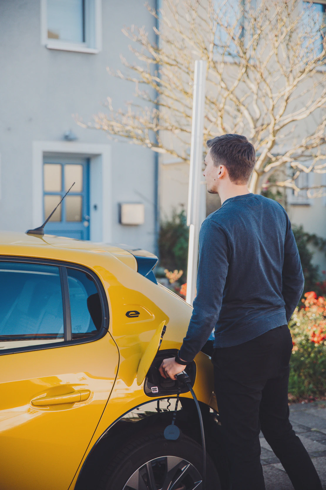 A man is charging his car in a residential area.